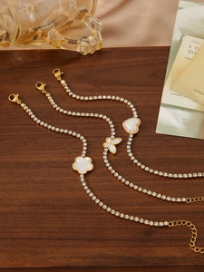 Detailed view of three gold-tone chain bracelets with flower, butterfly and heart charms