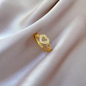 Κομψό χρυσό δαχτυλίδι καρδιά με κρύσταλλα micro-pave σε φόντο από μαλακό μετάξι
