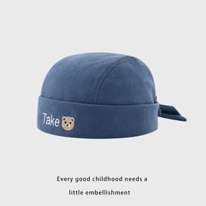 Détail du bonnet tricoté bleu marine pour bébé avec broderie ours et texte Take brodé