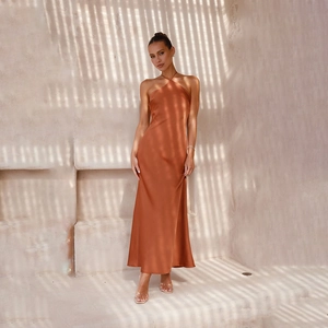 Detail of caramel satin fabric and open-back cut on the elegant halter neck maxi dress