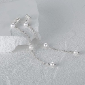 Close-up of S925 sterling silver chain earrings with three round white pearls on a stone