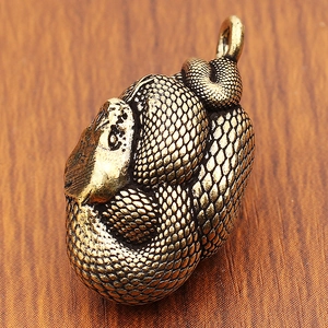 Dettaglio macro di un ciondolo a serpente in ottone con scaglie e texture vintage
