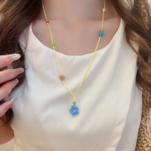 Detail of colorful beaded floral pendant necklace on neck with vibrant summer vibes