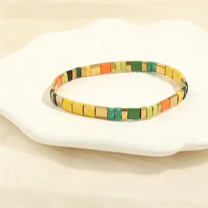 Detailed shot of multi-color Tila bead stretch bracelet in a decorative white shell dish