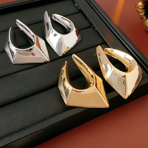 Macro shot of polished gold and silver irregular geometric stud earrings on a display tray