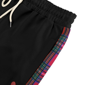 Detail of black jogger pants featuring plaid side stripes and a white adjustable drawstring