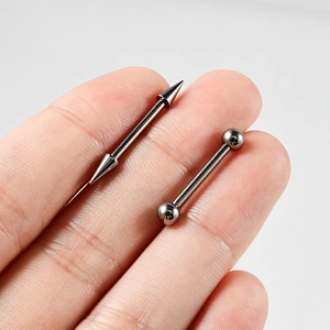 Macro detail of G23 titanium barbell body jewelry with cone and ball ends on finger