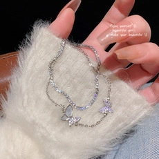 Detail of double-layer silver bracelet with butterfly pendant and pavé zircon tennis chain
