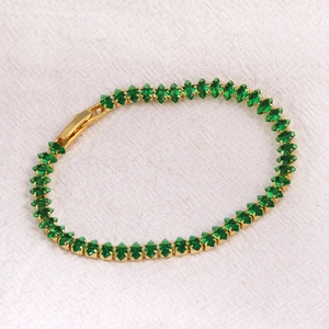Detailed close-up of gold-plated tennis bracelet featuring marquise-cut green zircons