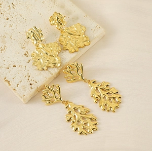 Detailed view of irregular 18K gold plated lava and coral-inspired earrings on stone