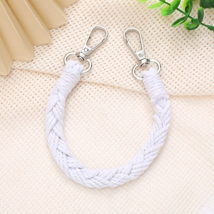 Detail of white hand-woven strap with silver metal swivel clasps on a grid background