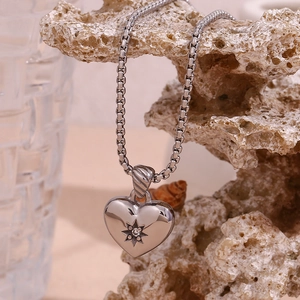 Macro detail of silver heart necklace with star-set zircon on natural coral stone