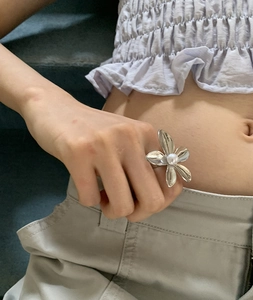 Macro detail of retro silver flower ring featuring textured petals and a center pearl