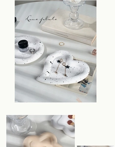 Macro detail of heart-shaped ceramic jewelry tray with black ink splatter finish