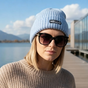 Bonnet en maille côtelée bleu clair avec patch HELLO porté par une femme en extérieur