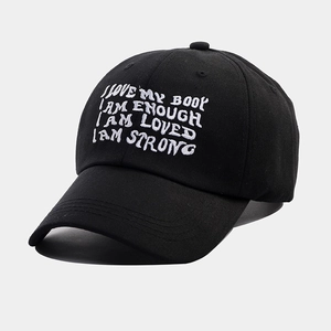 Detail view of white embroidered text on a black cotton baseball cap with a curved brim