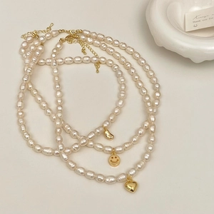 Close-up of freshwater pearl necklaces featuring gold heart and smiley face pendants