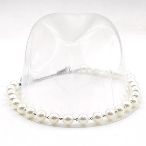 Close-up of elegant white faux pearl hat band with metal chain on a hat stand