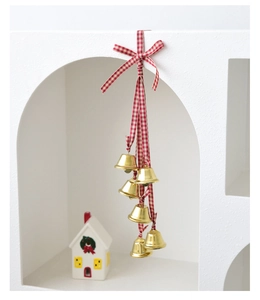 Close-up of golden Christmas bells with red and white plaid ribbon and a bow