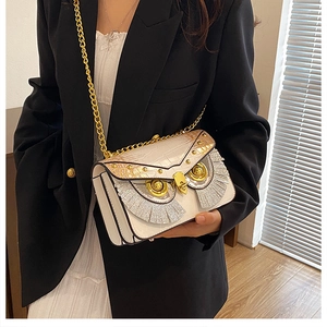 Détail du sac à bandoulière chouette avec texture crocodile et bandoulière en chaîne dorée