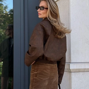 Dettaglio di un bomber in pelle vintage marrone e gonna di velluto a coste da donna