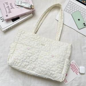 Macro shot of embroidered daisy tote bag with pastel threads and soft quilted texture