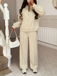 Detail of beige zip-up jacket and wide-leg pants set with metallic zipper pull