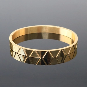 Detail of golden stainless steel bracelet with geometric triangular texture on black mirror