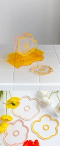 Detail of flower-shaped acrylic coasters in transparent and orange hues for home decor