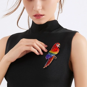 Vintage red parrot brooch with colorful rhinestones worn on a black knit top