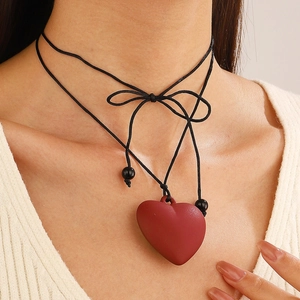 Gros plan du pendentif cœur rouge mat avec cordon noir et nœud décoratif chic