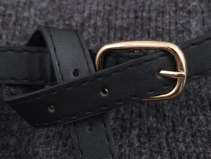 Close-up of black leather belt with golden metal buckle on knit fabric texture
