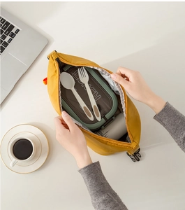 Top view of yellow insulated lunch bag interior with lunch box and cutlery on desk