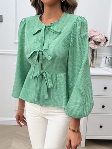 Detail of green and white plaid shirt featuring puff sleeves and three front bow ties
