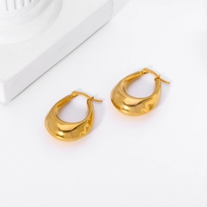 Close-up of polished 18K gold teardrop earrings with a mirror finish on a white background