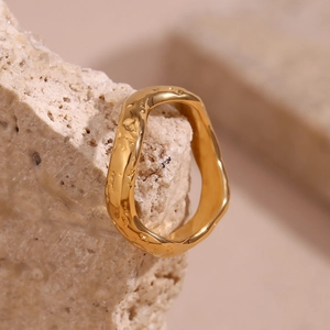 Detail of 18K gold plated ring with hammered texture resting on a beige stone
