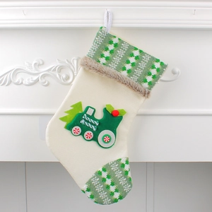 Beige Christmas stocking with green train applique hanging on a white fireplace