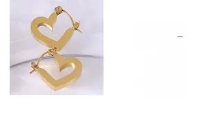 Detail view of heart-shaped gold earrings with a matte brushed finish on white fabric