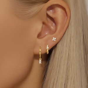 Detailed view of gold earrings set featuring flower studs and zircon pendants on ear