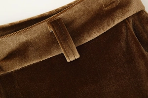 Detailed macro view of velvet flared trousers waistline and stitching in deep caramel