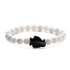 Detailed close-up of beaded bracelet with white beads and black blue sand fish charm