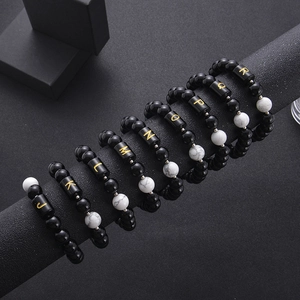 Detail of 10mm black onyx and white turquoise bracelets with gold letter beads