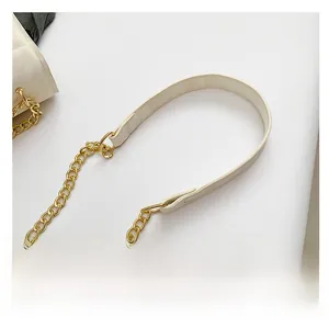 Detailansicht des gesteppten Lederriemens in Creme mit goldener Kette der Handtasche