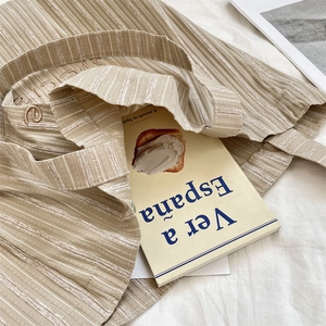 Detailed macro view of the textured striped canvas fabric and fine embroidery on the tote