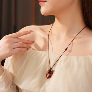 Close-up of bohemian wax rope necklace with red heart bead and silver floral details