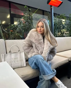 Detailed texture of women's beige faux fur coat featuring a oversized lapel design