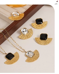 Detail of fan-shaped gold earrings and necklace set with black and clear square gemstones