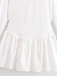 Detail of white batwing dress showing knitted texture and ruffled pleated waist seam