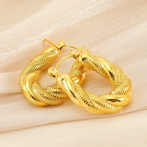 Gros plan détaillé de boucles d'oreilles dorées torsadées en U sur tissu de soie élégant