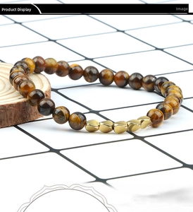 Detailed view of Tiger Eye beaded bracelet with irregular gold spacers on white grid background